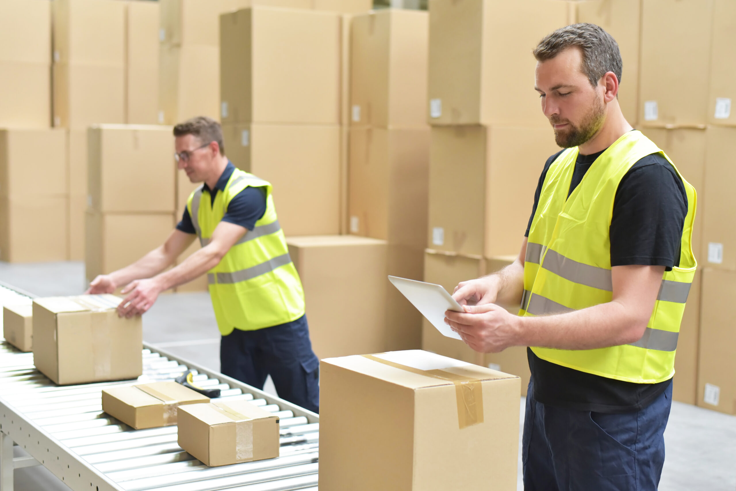Worker in a warehouse in the logistics sector processing packages on the assembly line – transport and processing of orders in trade